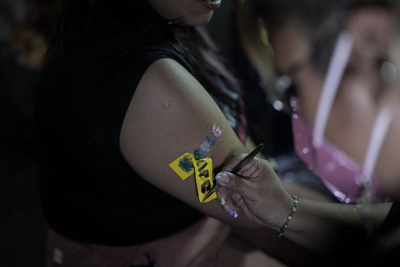 Una fan de Karol G se coloca un tatuaje temporal previo a un concierto de su gira Mañana será bonito en el Estadio Azteca de la Ciudad de México el jueves 8 de febrero de 2024. (Foto AP/Eduardo Verdugo)