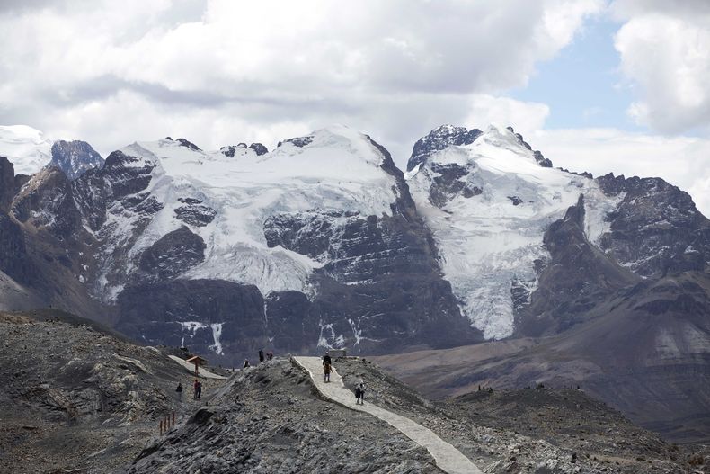 ARCHIVO - Turistas caminan frente al glaciar Tuco en el Parque Nacional de Huascarán durante un tour llamado Ruta por el cambio climático en Huaraz, Perú, el 12 de agosto de 2016. El país sudamericano ha perdido más de la mitad de la superficie de sus glaciares en las últimas seis décadas y 175 glaciares se extinguieron entre 2016 y 2020 como consecuencia del cambio climático, según anunciaron el miércoles 22 de noviembre de 2023 científicos de la agencia estatal de Perú que estudia los glaciares. (AP Foto/Martín Mejía, Archivo)