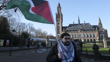 Un manifestante alza una bandera palestina frente al Palacio de la Paz, sede de la Corte Internacional de Justicia, el viernes 26 de abril de 2024, en La Haya, Holanda. (AP Foto/Patrick Post)