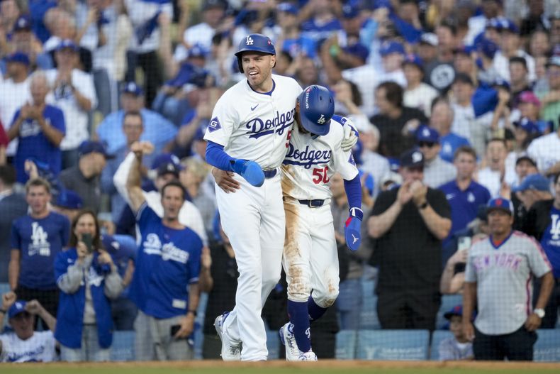 Freddie Freeman (izquierda) y Mookie Betts, de los Dodgers de Los Ángeles, festejan tras anotar en un sencillo durante el primer juego de la Serie de Campeonato de la Liga Nacional ante los Mets de Nueva York, el domingo 13 de octubre de 2024 (AP Foto/Ashley Landis)