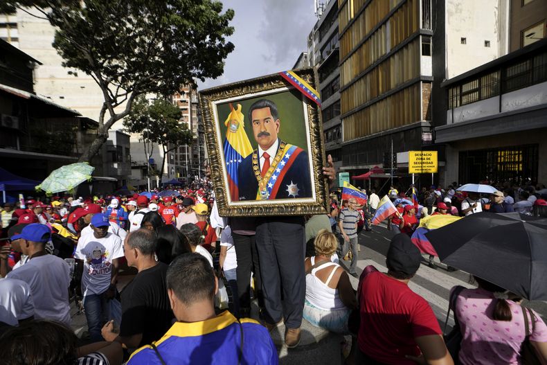 Un partidario sostiene una imagen enmarcada del presidente Nicolás Maduro mientras la gente se reúne para un mitin del gobierno en Caracas, Venezuela, el sábado 3 de agosto de 2024. (Foto AP/Matías Delacroix)