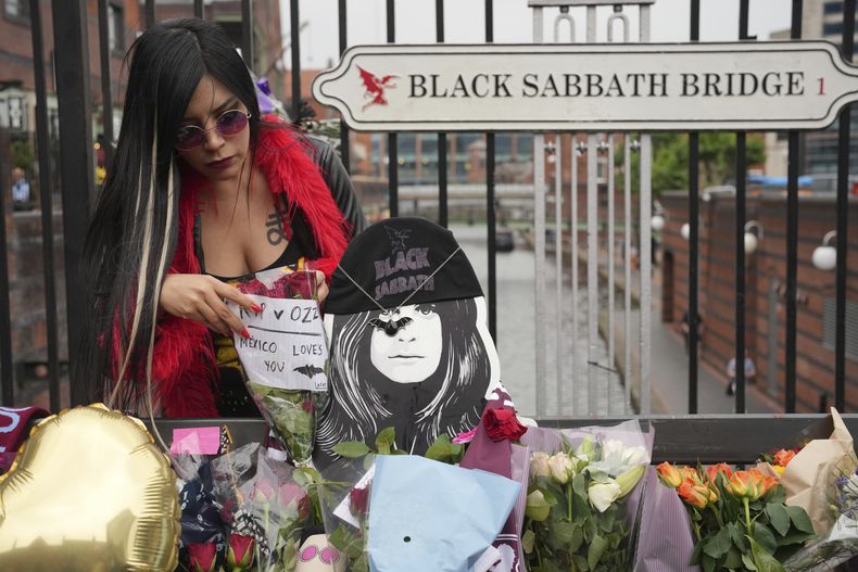 Lesley Venegas coloca flores para conmemorar la muerte de Ozzy Osbourne en el puente Black Sabbath en Birmingham, el miércoles 23 de julio de 2025. (Foto AP/Kin Cheung)