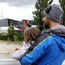 Un hombre con un niño en brazos contempla la crecida del río Santerno, y en el fondo de ve el circuito Enzo e Dino Ferrari en Imola, Italia, 17 de mayo de 2023. Las inundaciones en la región han obligado a cancelar el Gran Premio de Fórmula Uno de la Emilia Romagna, que se debía correr en Imola el próximo fin de semana. (AP Foto/Luca Bruno)