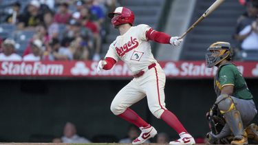 Taylor Ward (3), de los Angelinos de Los Ángeles, batea cuadrangular mientras el receptor de los Atléticos de Oakland, Shea Langeliers, observa durante la primera entradad el juego de béisbol del lunes 24 de junio de 2024, en Anaheim California. (AP Foto/Eric Thayer)