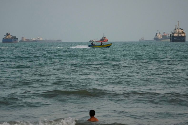 Una persona nada en la costa y al fondo se ven anclados buques en el estrecho de Ormuz, en Bandar Abbas, Irán, el 4 de septiembre 2026. (AP Foto/Vahid Salemi)