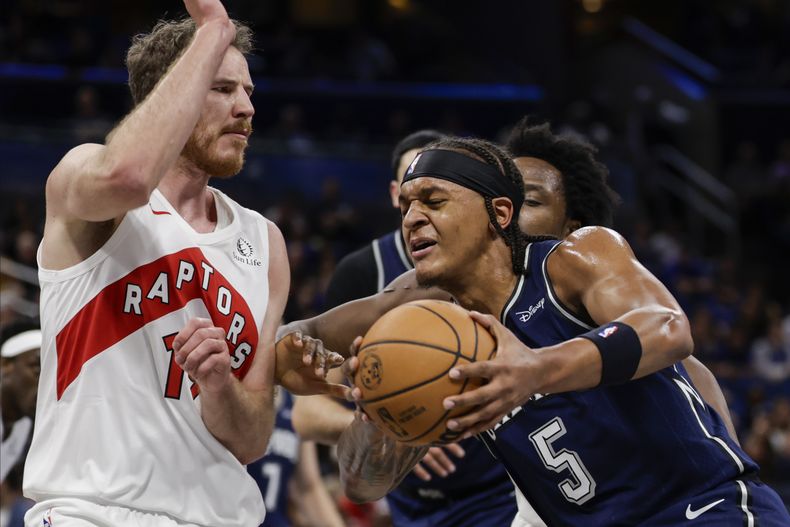 Paolo Banchero, del Magic de Orlando, avanza frente a Jakob Poeltl, de los Raptors de Toronto, durante el partido el martes 21 de noviembre de 2023 (AP Foto/Kevin Kolczynski)
