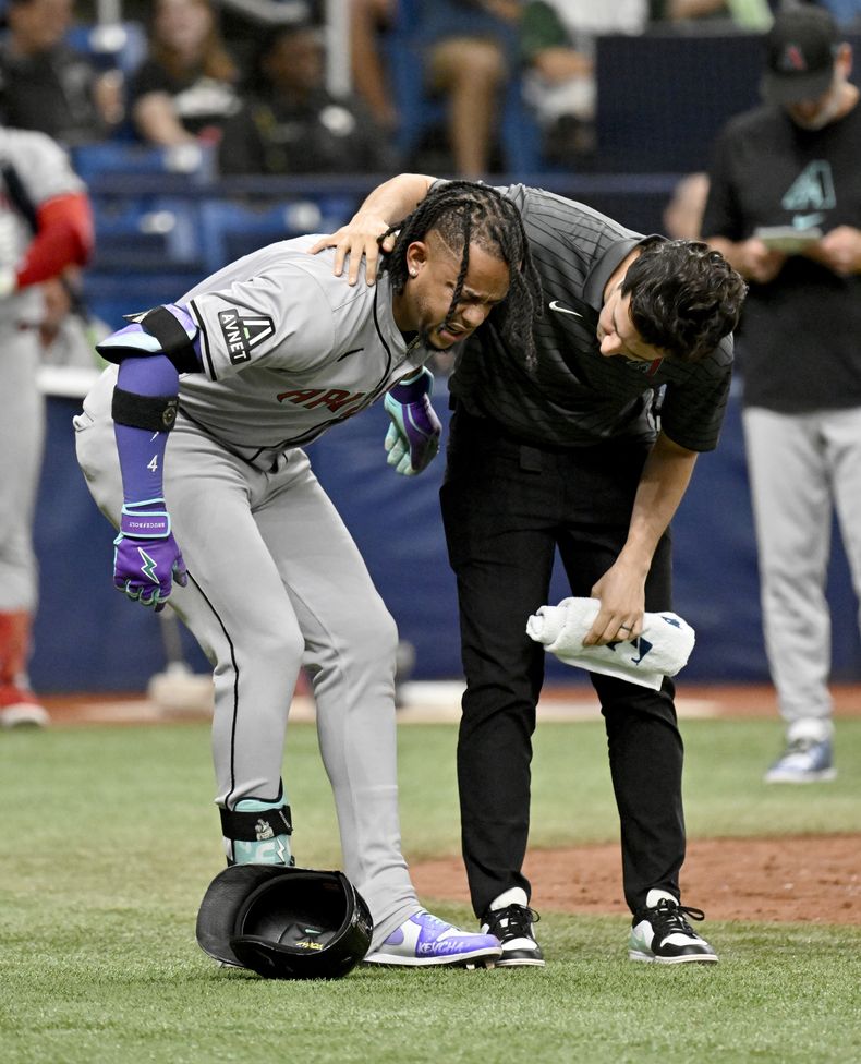 Ketel Marte, a la izquierda, de los Diamondbacks de Arizona, recibe ayuda tras lesionarse mientras bateaba durante la décima entrada contra los Rays de Tampa Bay, el domingo 18 de agosto de 2024, en St. Petersburg, Florida (AP Foto/Jason Behnken)