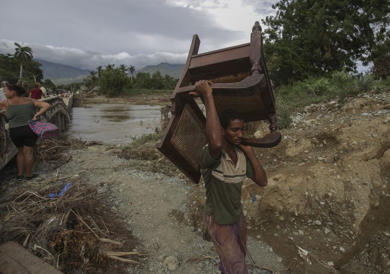Un hombre lleva una silla cerca de un río una semana después de que el huracán Oscar azotara la ciudad de Imías en la provincia de Guantánamo, Cuba, el martes 29 de octubre de 2024. (AP Foto/Ariel Ley, Pool)