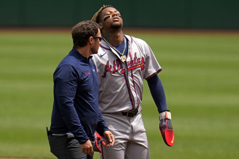 ARCHIVO - Ronald Acuña Jr., de los Bravos de Atlanta, abandona el terreno con un kinesiólogo, luego de lastimarse en el duelo ante los Piratas de Pittsburgh, el domingo 26 de mayo de 2024 (AP Foto/Gene J. Puskar, archivo)