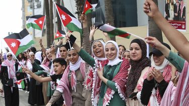 Jordanos ondean banderas previo a que pase la caravana del príncipe heredero Hassan y su esposa Rajwa Alseif, durante las celebraciones por su boda, en Amán, el jueves 1 de junio de 2023. (AP Foto/Raad Adayleh)