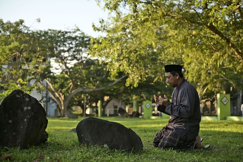 Un hombre reza en una fosa común pasa las víctimas del tsunami de 2004 en el océano Índico, en Banda Aceh, Indonesia, el 26 de diciembre de 2024. (AP Foto/Reza Saifullah)