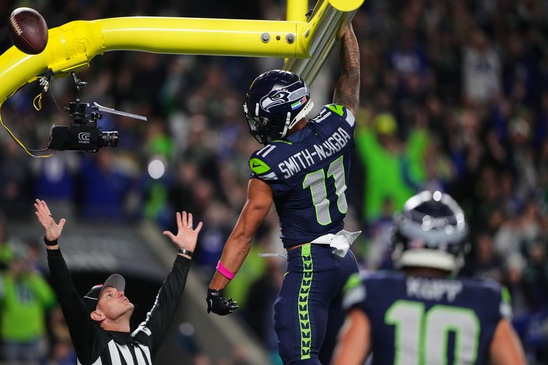 Jaxon Smith-Njigba (11), wide receiver de los Seahawks de Seattle, celebra una recepción de touchdown mientras el árbitro marca la anotación y observa durante la primera mitad del partido de la NFL en contra de los Texans de Houston, el lunes 20 de octubre de 2025, en Seattle. (AP Foto/Lindsey Wasson)