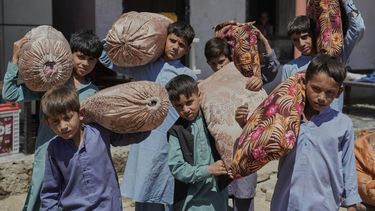 Niños afganos de familias repatriadas de Pakistán cargan cojines mientras se desplazan a su nuevo lugar de residencia, en Kabul, Afganistán, el martes 3 de junio de 2025. (AP Foto/Ebrahim Noroozi)