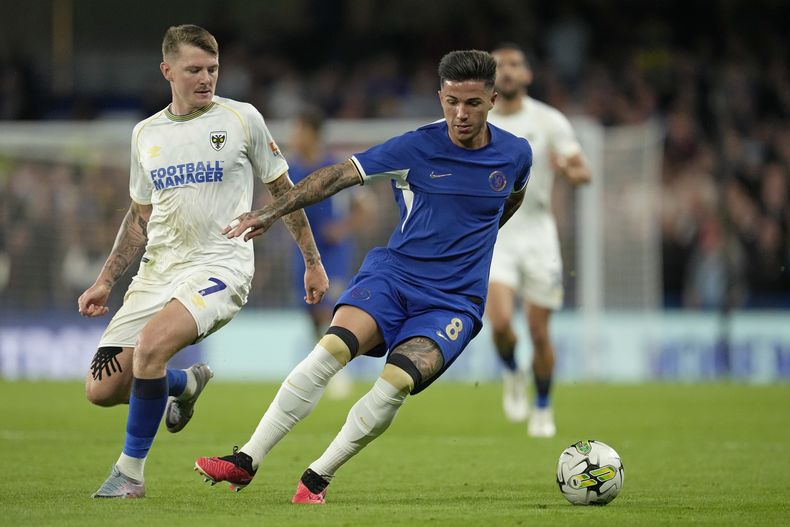 El argentino Enzo Fernandez del Chelsea pelea por el balón James Tilley del Wimbledon en el encuentro de la Copa de Liga el miércoles 30 de agosto del 2023. (AP Foto/Kin Cheung)