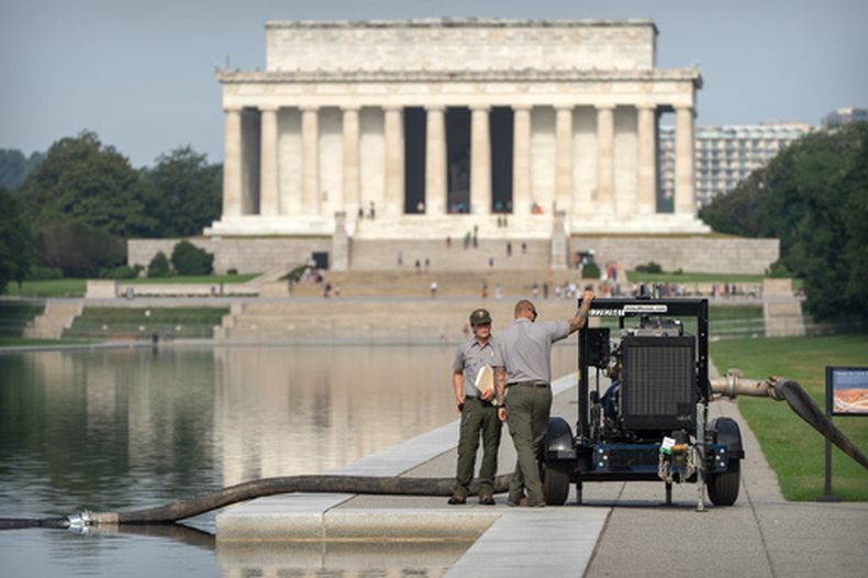 Trabajadores del Servicio de Parques Nacionales permanecen junto a una bomba situada al lado del estanque reflectante del Monumento a Lincoln, el viernes 10 de julio de 2026, en Washington. (Foto AP/Mark Schiefelbein)