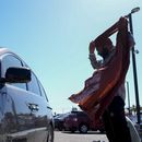 Un migrante ajusta su pañuelo en un estacionamiento tras ser detenido y procesado para recibir asilo por las autoridades de Estados Unidos, el martes 7 de mayo de 2024, en San Diego. (AP Foto/Ryan Sun)