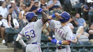 Adolis Garcia (53), de los Rangers de Texas, felicita a Josh Jung en el plato después del cuadrangular frente al abridor de los Medias Blancas de Chicago, Tanner Banks, durante la tercera entrada del juego de béisbol el lunes 19 de junio de 2023, en Chicago. (AP Foto/Charles Rex Arbogast)