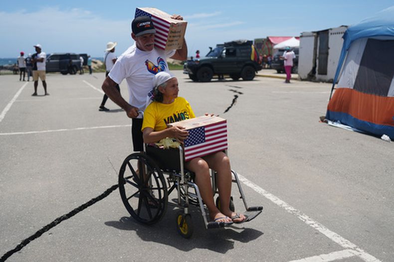 Personas afectadas por los sismos llevan ayuda humanitaria proveniente de Estados Unidos en La Guaira, Venezuela, el 8 de julio del 2026. (AP foto/Ariana Cubillos)