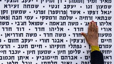 Una mujer toca la pared con los nombres de soldados israelíes fallecidos en el sitio conmemorativo en Latrun, Israel, el lunes 13 de mayo de 2024. (AP Foto/Ariel Schalit)