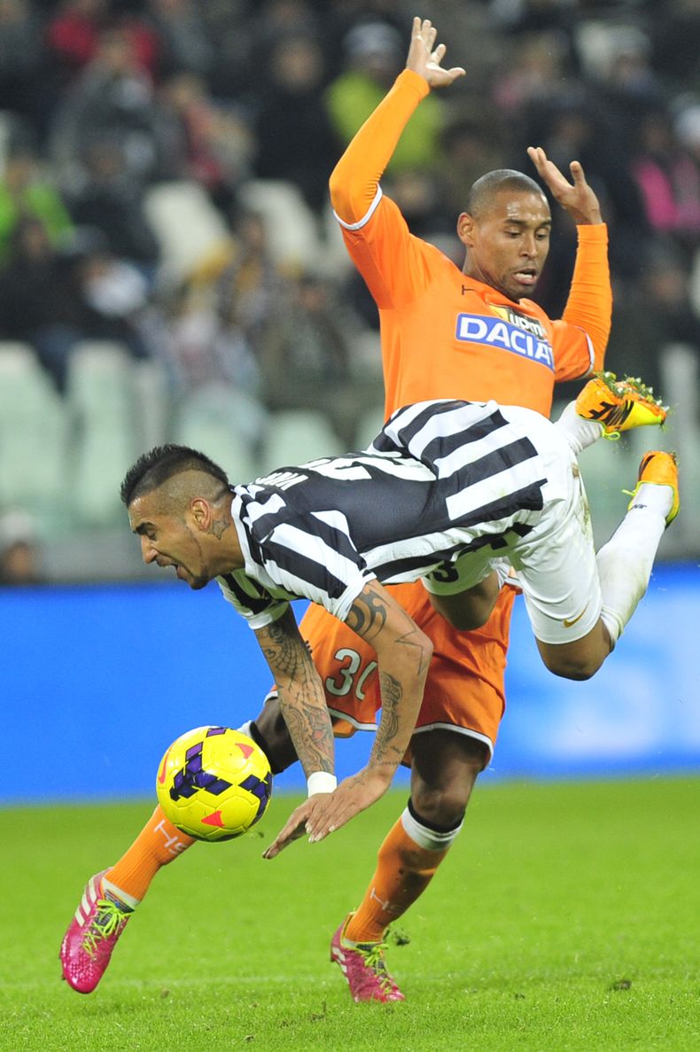 El jugador de la Juventus, Arturo Vidal, al frente, cae al disputar un bal&oacute;n en un partido con Udinese el domingo, 1 de diciembre de 2013, en Tur&iacute;n, Italia. (AP Photo/Massimo Pinca)