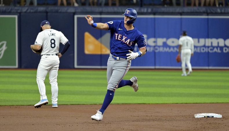 Josh Jung de los Rangers de Texas saluda al bullpen de su equipo al recorrer las bases tras conectar un jonrón de tres carreras frente a los Rays de Tampa Bay el lunes 1 de abril del 2024. (AP Foto/Steve Nesius)