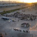 A medida que el sol se pone, migrantes aguardan afuera de una puerta en la cerca fronteriza el jueves 11 de mayo de 2023 para ingresar a El Paso, Texas, con el fin de que la Patrulla Fronteriza procese sus casos. Gran cantidad de migrantes se apresuraron a cruzar la frontera con México, en un intento apresurado por ingresar a Estados Unidos antes de que llegara a su fin una norma que restringía el asilo, en un cambio de política que amenaza con agobiar aún más el sistema migratorio de Estados Unidos. (AP Foto/Andrés Leighton)