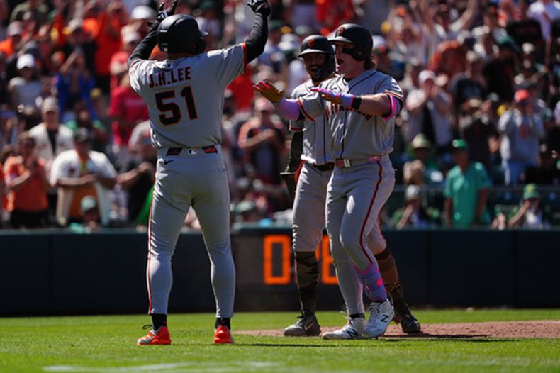 Harrison Bader, derecha, de los Gigantes de San Francisco, es felicitado en el plato por Jung Hoo Lee (51) después de disparar un grand slam en la octava entrada del juego de béisbol de Grandes Ligas contra los Atléticos, el domingo 17 de mayo de 2026, en West Sacramento, California. (AP Foto/Alan Greth)