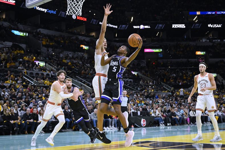 DeAaron Fox (5) de los Kings de Sacramento va hacia el aro ante Jeremy Sochan de los Spurs de San Antonio durante la primera mitad del juego de NBA, el viernes 17 de noviembre de 2023, en San Antonio. (AP Foto/Darren Abate)