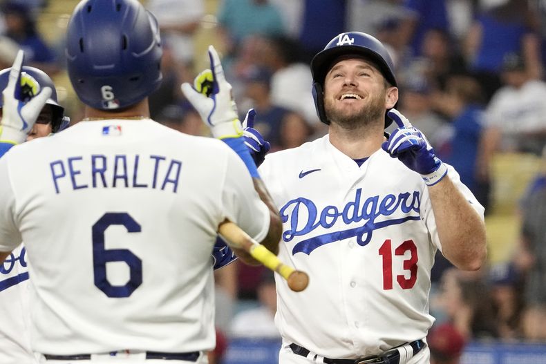 Max Muncy (derecha), de los Dodgers de Los Ángeles, recibe la felicitación de su compañero David Peralta tras sacudir un jonrón de dos carreras en el primer inning del juego de la MLB que enfrentò a su equipo con los Diamondbacks de Arizona, el 28 de agosto de 2023, en Los Ángeles. (AP Foto/Mark J. Terrill)