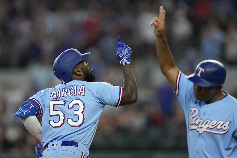 Adolis Garcia (53), de los Rangers de Texas, y el coach de tercera base Tony Beasley, derecha, celebran después del cuadrangular solitario de García en la octava entrada del juego de béisbol en contra de los Marlins de Miami, el domingo 6 de agosto de 2023, en Arlington, Texas. (AP Foto/Tony Gutierrez)