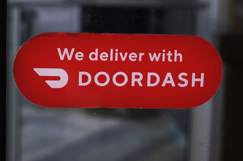 Un letrero del servicio de entrega de comidas DoorDash en la puerta de una franquicia de Dunkin Donuts, el 27 de febrero de 2023, en Methuen, Massachusetts. (AP Foto/Charles Krupa, Archivo)
