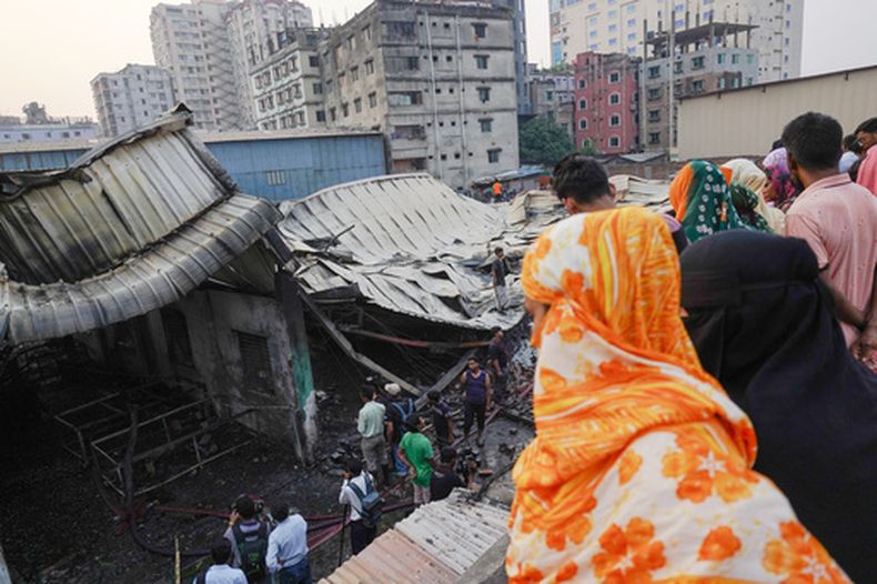 Varias personas observan los restos calcinados de una fábrica de encendedores de gas en Keraniganj, en las afueras de Daca, Bangladesh, el sábado 4 de abril de 2026. (Foto AP/MD. Samsul Islam Hady)