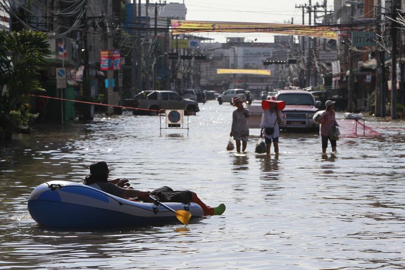Varios tratan de vadear las calles anegadas de un pueblo de la provincia de Prachinburi, en Tailandia, el martes 1 de octubre del 2013. Las autoridades tailandesas dijeron el martes que las inundaciones hab&iacute;an causado la muerte a m&aacute;s de 20 p