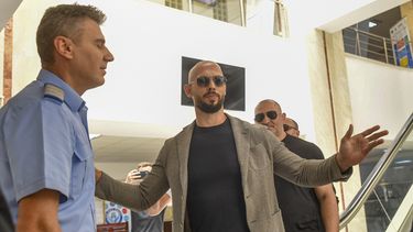 Andrew Tate gesticula junto a un gendarme al salir del tribunal en Bucarest junto su hermano Tristan, derecha, tras la primera audiencia de su juicio, 21 de junio de 2023. Una corte rumana el viernes 23 de junio de 2023 extendió en 30 días el arresto domiciliario de Andrew Tate, el polémico personaje de las redes sociales y exkickboxer profesional acusado de violación, tráfico de seres humanos y creación de una pandilla para explotar sexualmente a mujeres. (AP Foto/Alexandru Dobre)