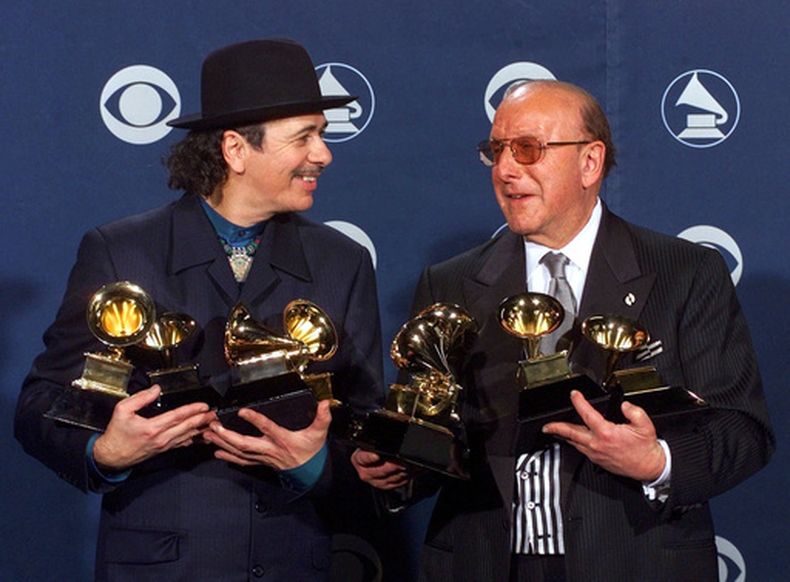 ARCHIVO - Carlos Santana, a la izquierda, y el productor Clive Davis posan con sus premios Grammy en la 42ª edición de los Premios Grammy en Los Ángeles, el 23 de febrero de 2000. (Foto AP/Reed Saxon, archivo)