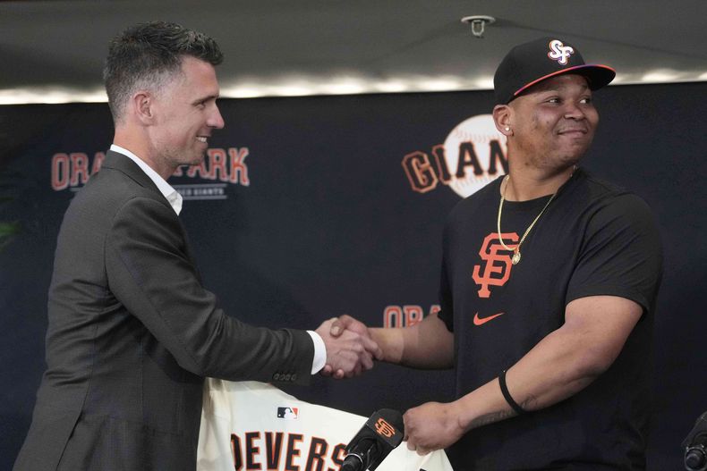 Buster Posey, presidente de operaciones deportivas de los Gigantes de San Francisco, estrecha la mano del dominicano Rafael Devers, antes de un juego ante los Guardianes de Clveland (AP Foto/Jeff Chiu)