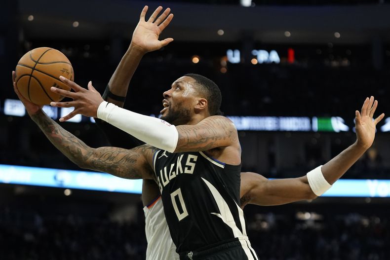 Damian Lillard (0), de los Bucks de Milwaukee, dispara contra OG Anunoby, de los Knicks de Nueva York, durante la segunda mitad de un partido de baloncesto de la NBA, el domingo 7 de abril de 2024, en Milwaukee. (AP Foto/Aaron Gash)