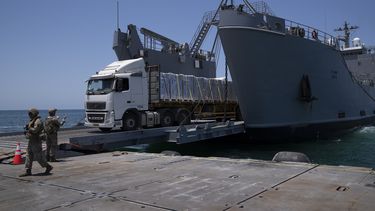 Un soldado del ejército estadounidense da instrucciones a un camión cargado con ayuda humanitaria que desembarca en el muelle flotante construido por Estados Unidos, antes de llegar a la playa, en la costa de la Franja de Gaza, el martes 25 de junio de 2024. (AP Foto/Leo Correa)