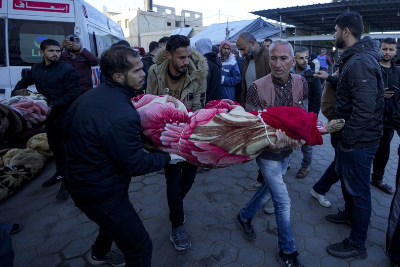 Palestinos llevan el cuerpo de un familiar muerto en el bombardeo israelí de la Franja de Gaza en un hospital de Deir al-Balah, domingo 15 de diciembre de 2024. (AP foto/Abdel Kareem Hana)