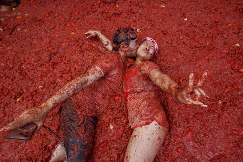 Una pareja se besa sobre un charco de tomates durante la Tomatina en el pueblo de Buñol, cerca de Valencia, España, el miércoles 27 de agosto de 2025. (AP Foto/Alberto Saiz)