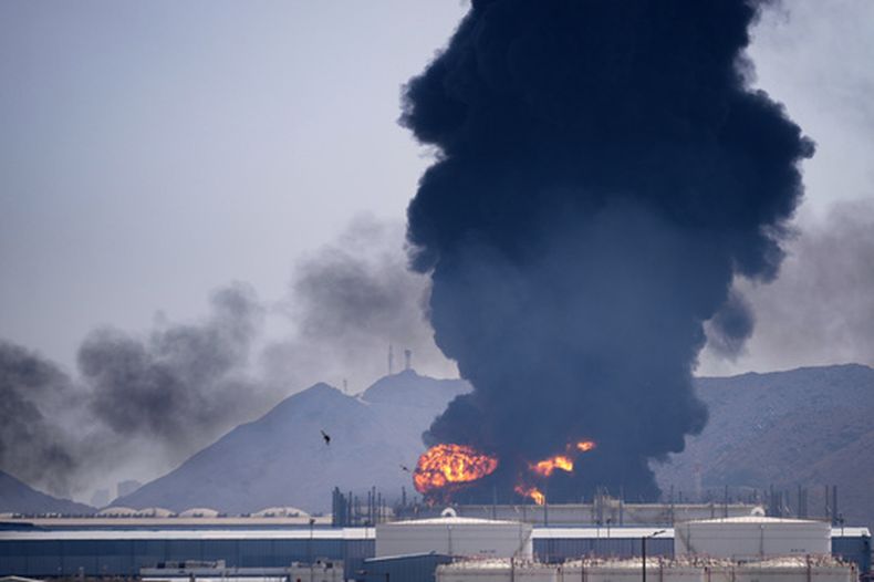 Según las autoridades, una llamarada y una columna de humo se elevan tras el impacto de los restos de un dron iraní interceptado contra una instalación petrolera, el sábado 14 de marzo de 2026, en Fujairah, Emiratos Árabes Unidos. (AP Foto/Altaf Qadri)