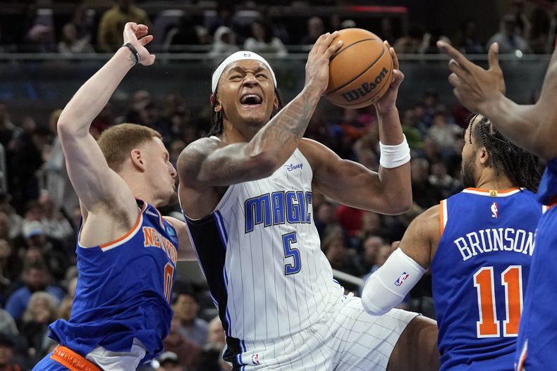 El alero del Magic de Orlando Paolo Banchero (5) salta ante la defensa de Donte DiVicenzo (izquierda) y Jalen Brunson (1) de los Knicks de Nueva York durante la segunda mitad del juego de NBA, el viernes 29 de diciembre de 2023, en Orlando, Florida. (AP Foto/John Raoux)