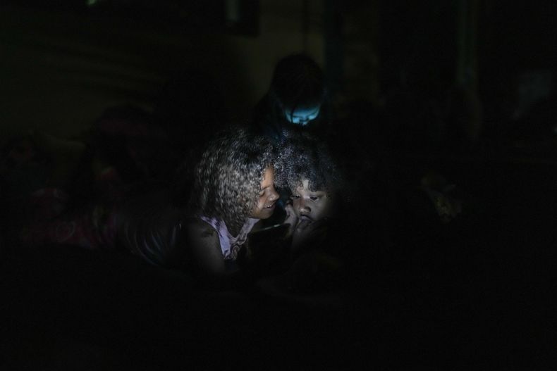 Hijos de migrantes venezolanos juegan con un teléfono celular en Puerto Cartí, en la costa caribeña de Panamá, el sábado 22 de febrero de 2025, donde planean tomar una embarcación a Colombia en su camino de regreso desde el sur de México después de perder las esperanzas de llegar a Estados Unidos en medio de la ofensiva del presidente Donald Trump contra la migración. (Foto AP/Matías Delacroix)