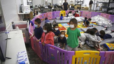 En esta imagen del 30 de marzo de 2021, migrantes menores sin compañía de un adulto ven televisión dentro de un corral de juegos en una instalación de la Oficina de Aduanas y Protección Fronteriza, el principal centro de detención para niños no acompañados en el Rio Grande Valley, en Donna, Texas. (AP Foto/Dario Lopez-Mills, Pool, Archivo)
