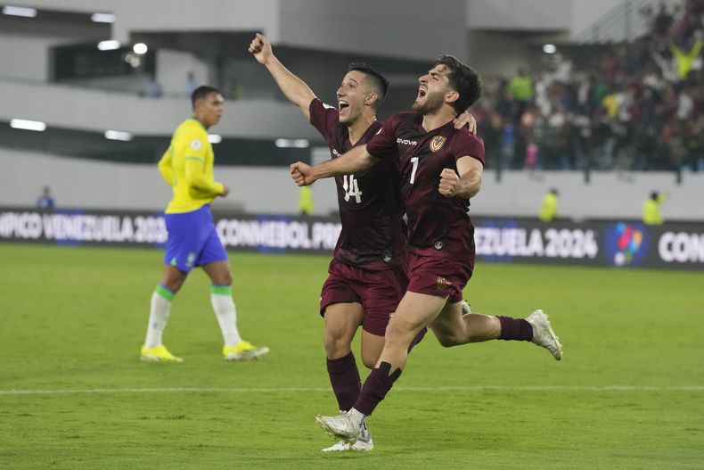 Carlos Faya (izquierda) y Matías Lacava, de la selección de Venezuela, festejan un autogol de Brasil en un partido del Preolímpico Sudamericano, el jueves 1 de febrero de 2024, en Caracas (AP Foto/Ariana Cubillos)