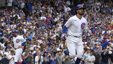 Dansby Swanson (derecha) de los Cachorros de Chicago avanza hacia primera base, mientras que Mike Tauchman (al fondo izquierdo) anota durante la tercera entrada ante los Bravos de Atlanta, en Chicago. Doming 6 de agosto de 2023 (AP Foto/Nam Y. Huh)