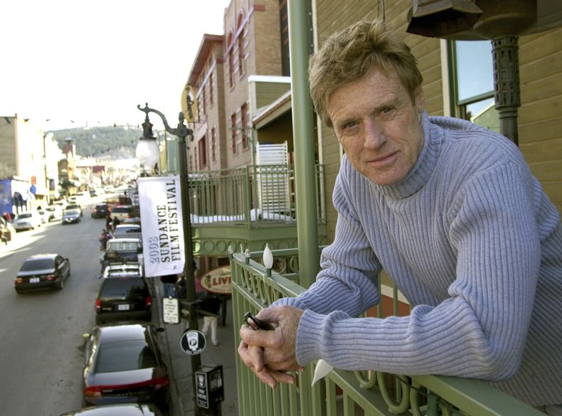 ARCHIVO - Robert Redford posa en un balcón en Main Street decorado con sus pancartas del Festival de Cine de Sundance el 17 de enero de 2003, en Park City, Utah. (Foto AP/Douglas C. Pizac, archivo)