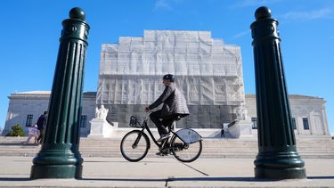 Una persona pasa en bicicleta frente a la construcción que se realiza en el frente de la Corte Suprema de Estados Unidos, el lunes 24 de noviembre de 2025, en Washington. (AP Foto/Mariam Zuhaib)