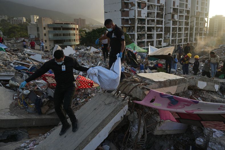Miembros del Cuerpo de Investigación Científica, Penal y Criminalística de Venezuela recuperan el cuerpo de una de las dos hijas de Yolimar Torres, a quien la familia encontró entre los escombros de un edificio derrumbado por los dos terremotos, en La Guaira, Venezuela, el miércoles 15 de julio de 2026. (Foto AP/Ariana Cubillos)