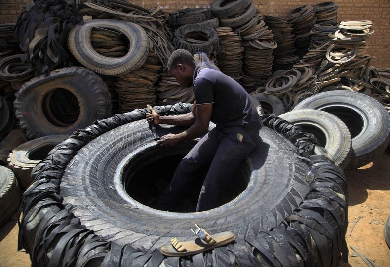 ARCHIVO - Un sudanés corta un neumático para trabajo pesado en trozos de hule, el 12 de mayo de 2014, en un mercado en Omdurmán, Jartum, Sudán. (AP Foto/Abd Raouf, archivo)